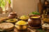 Traditional Indian kitchen featuring a brass bowl of Pure A2 Cow Ghee, a clay pot of Buffalo Bilona Ghee, fresh rotis, dal, rice, wooden cooking utensils, and rustic farm-inspired decor representing the return of traditional nutrition in Indian homes.